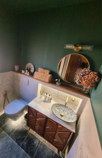 Dark green statement cloakroom with decorative basin and round mirror by Misbourne Plumbing