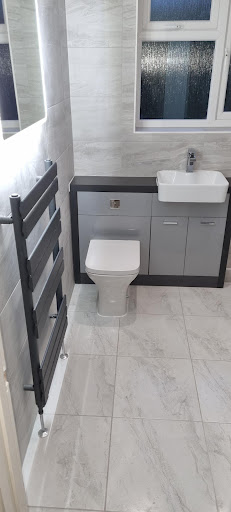 Contemporary grey bathroom with heated towel rail and marble-effect tiles by Misbourne Plumbing